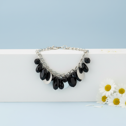 Silver Necklace with black beads on a white surface with flowers