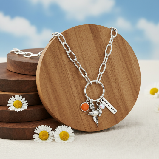 Inspired Songbird necklace on honey wood disc with blue sky background and daisies
